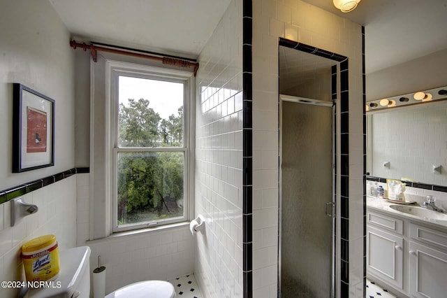 bathroom with vanity, toilet, an enclosed shower, and tile walls