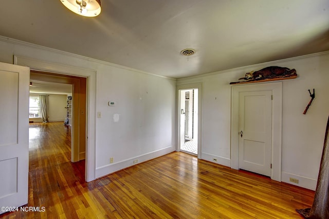 empty room with hardwood / wood-style flooring and ornamental molding