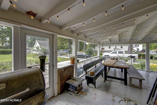 sunroom / solarium featuring beamed ceiling and rail lighting