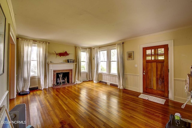 unfurnished living room with ornamental molding, a brick fireplace, and hardwood / wood-style floors