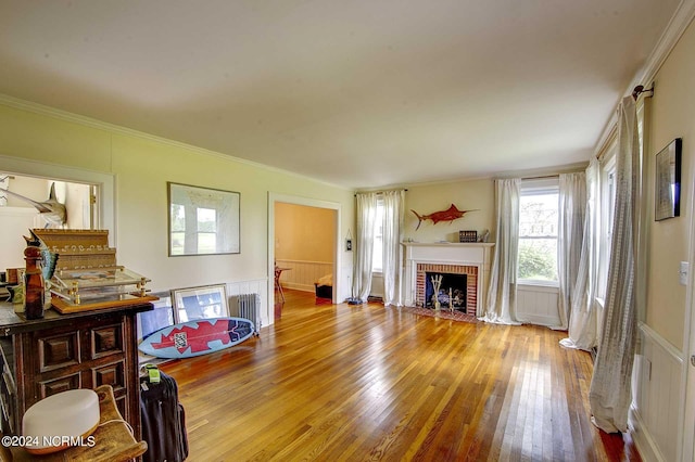 living room with ornamental molding, radiator heating unit, a fireplace, and light hardwood / wood-style floors