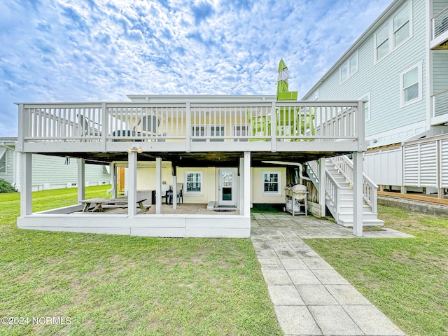 back of house featuring a deck, a patio, and a lawn