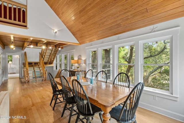 dining area with wood ceiling, a wealth of natural light, lofted ceiling with beams, and light wood-type flooring