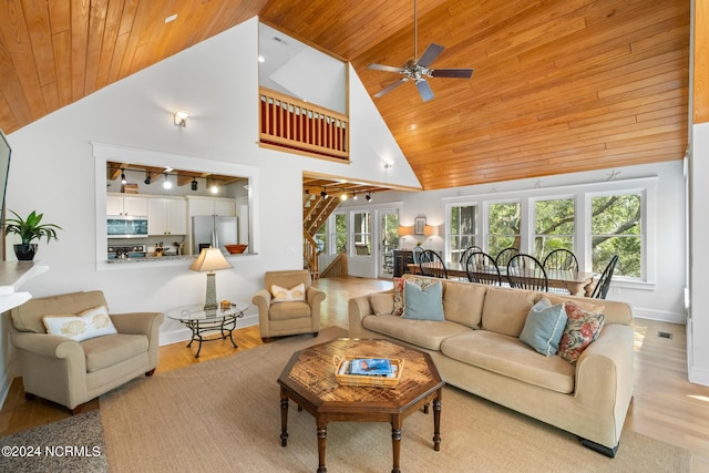 living room with rail lighting, high vaulted ceiling, wood ceiling, and light hardwood / wood-style flooring