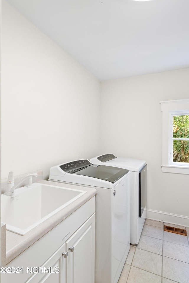 clothes washing area featuring cabinets, washing machine and clothes dryer, light tile patterned flooring, and sink