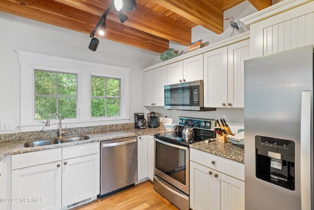 kitchen with white cabinetry, stainless steel appliances, stone countertops, and sink