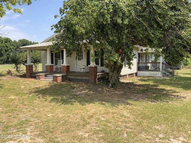 view of property hidden behind natural elements with a porch and a front lawn