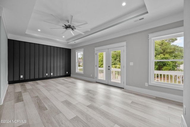 empty room featuring french doors, ceiling fan, a tray ceiling, and light hardwood / wood-style floors