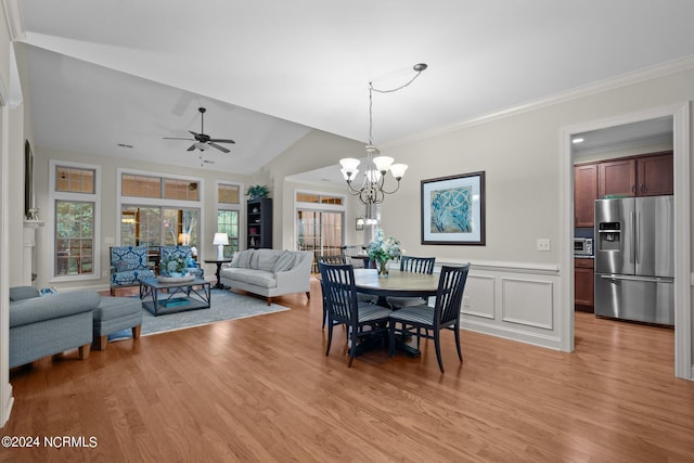 dining area featuring vaulted ceiling, ceiling fan with notable chandelier, crown molding, and light hardwood / wood-style flooring