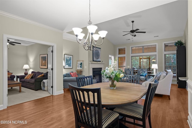 dining space with crown molding, hardwood / wood-style flooring, ceiling fan with notable chandelier, and vaulted ceiling