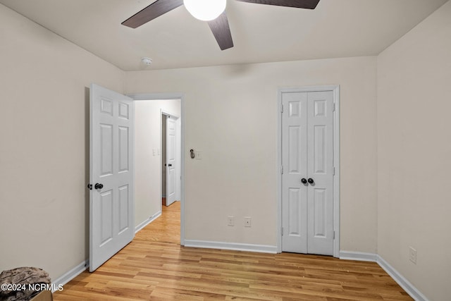 unfurnished bedroom with light wood-type flooring, ceiling fan, and a closet