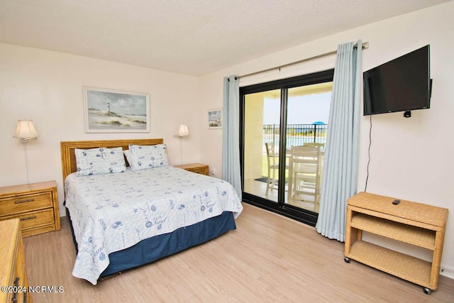 bedroom with light wood finished floors, access to outside, and a textured ceiling