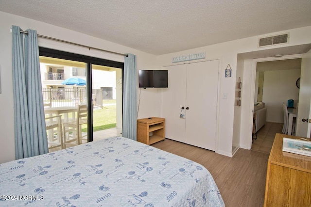 bedroom featuring a textured ceiling, visible vents, access to exterior, a closet, and light wood finished floors