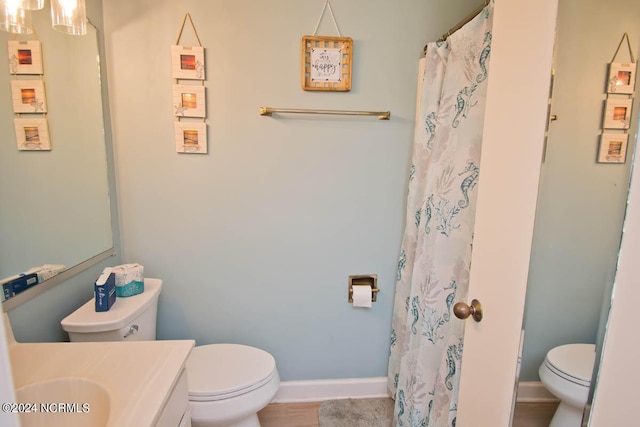 full bathroom with baseboards, vanity, and toilet