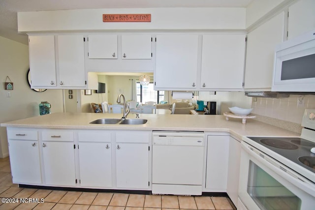 kitchen featuring light countertops, white appliances, a peninsula, and a sink