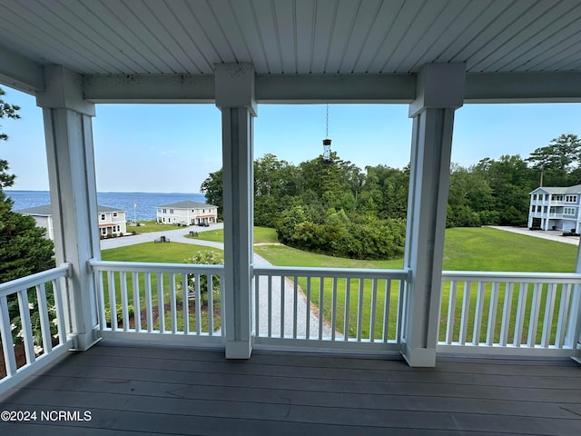 wooden terrace featuring a water view, a porch, and a yard