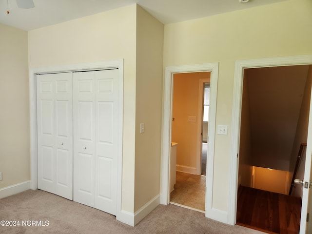 unfurnished bedroom featuring ceiling fan, light carpet, and a closet