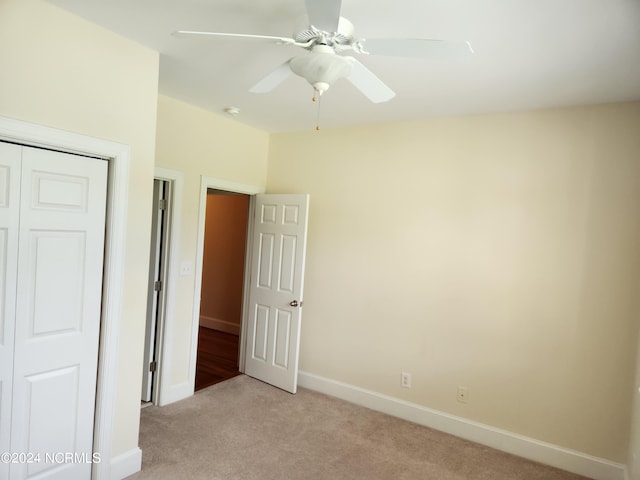 unfurnished bedroom with ceiling fan, light colored carpet, and a closet