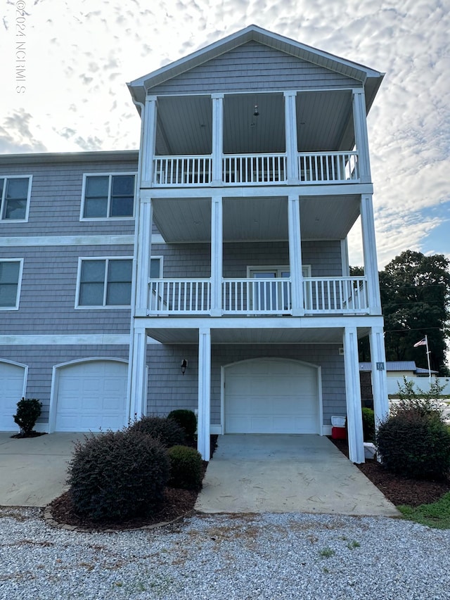 coastal inspired home with driveway, a balcony, and an attached garage