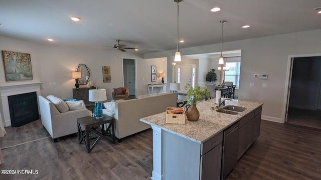 kitchen with decorative light fixtures, an island with sink, a kitchen bar, light stone counters, and stainless steel appliances