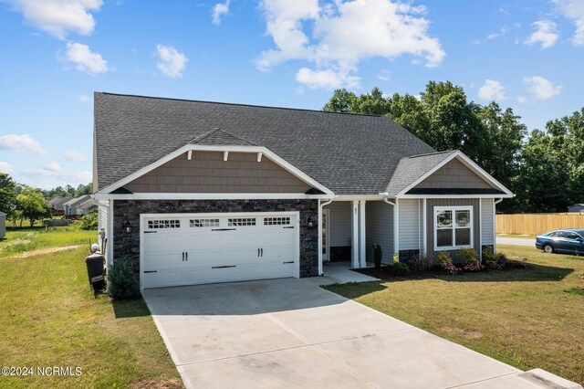 craftsman-style home with an attached garage, driveway, stone siding, roof with shingles, and a front lawn