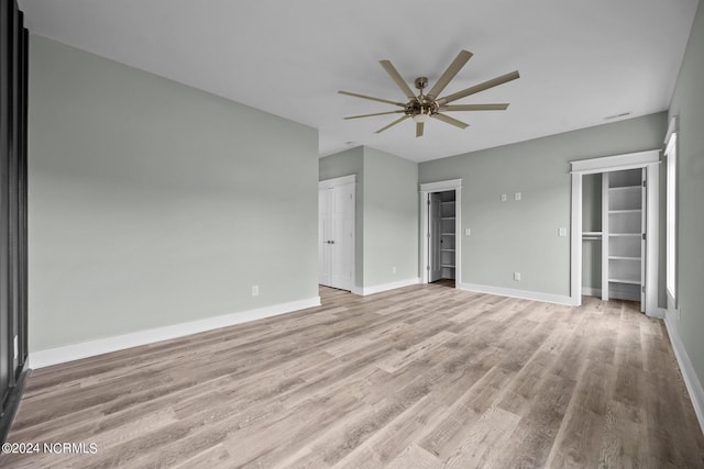 unfurnished bedroom featuring two closets, ceiling fan, and light wood-type flooring