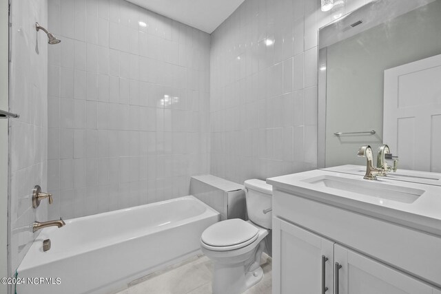 full bathroom with tiled shower / bath, vanity, toilet, and tile walls