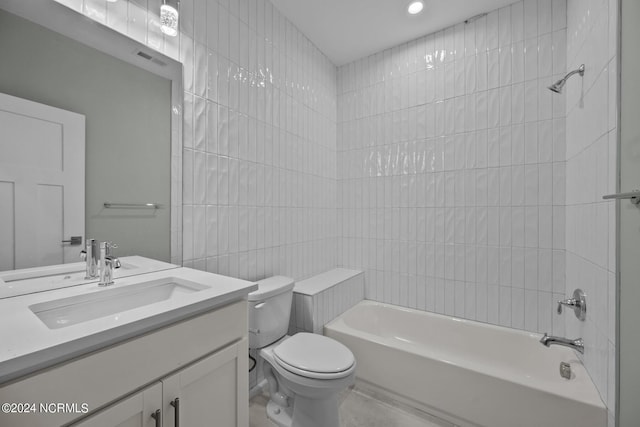 full bathroom with tiled shower / bath combo, vanity, tile walls, and toilet