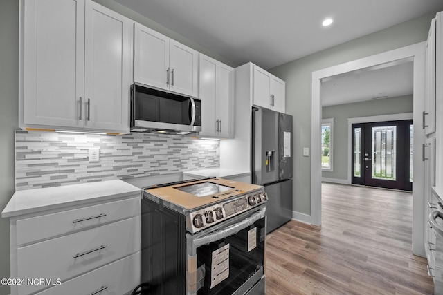 kitchen featuring white cabinetry, appliances with stainless steel finishes, light hardwood / wood-style floors, and decorative backsplash