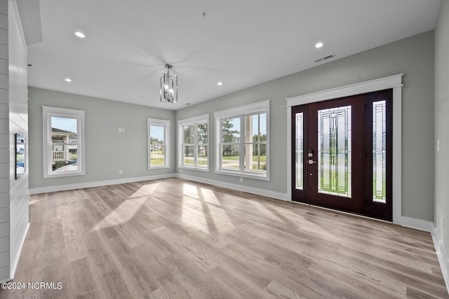 unfurnished living room with a chandelier and light wood-type flooring