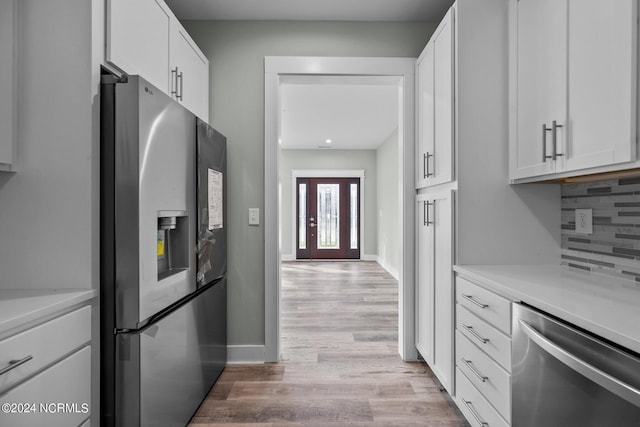 kitchen featuring tasteful backsplash, white cabinetry, appliances with stainless steel finishes, and light hardwood / wood-style floors