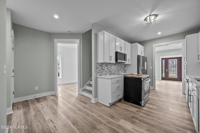 kitchen with white cabinetry, appliances with stainless steel finishes, backsplash, and light hardwood / wood-style floors