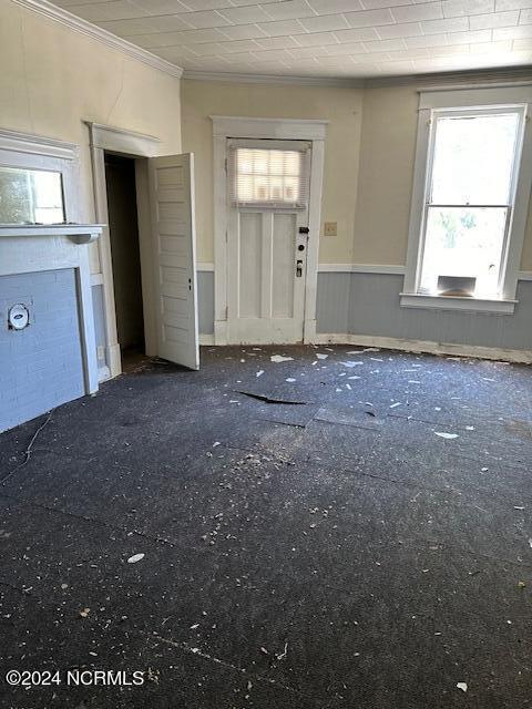 unfurnished living room featuring crown molding and dark colored carpet