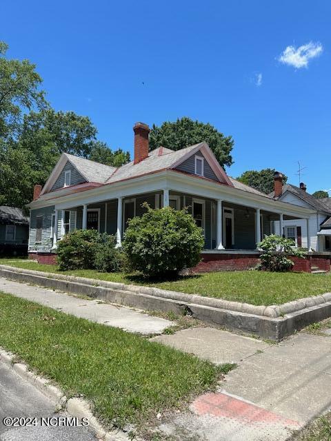 farmhouse featuring a porch and a front yard