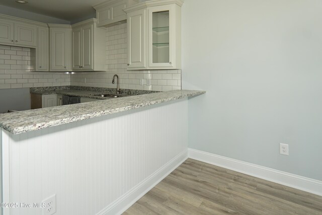 unfurnished living room with sink, light hardwood / wood-style floors, and vaulted ceiling