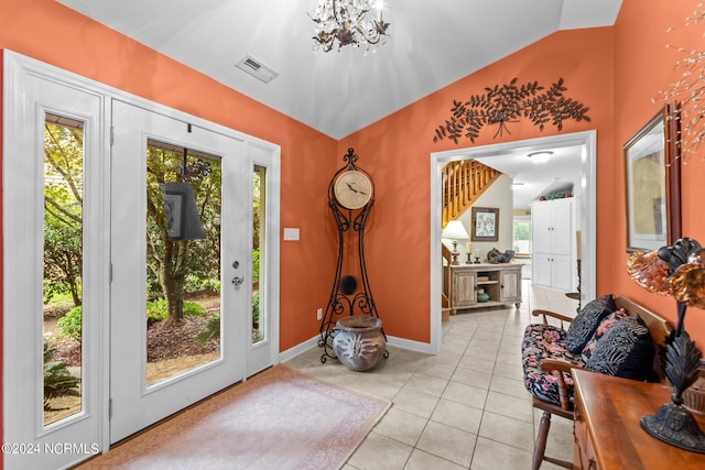 entryway featuring lofted ceiling, light tile patterned flooring, a notable chandelier, visible vents, and baseboards