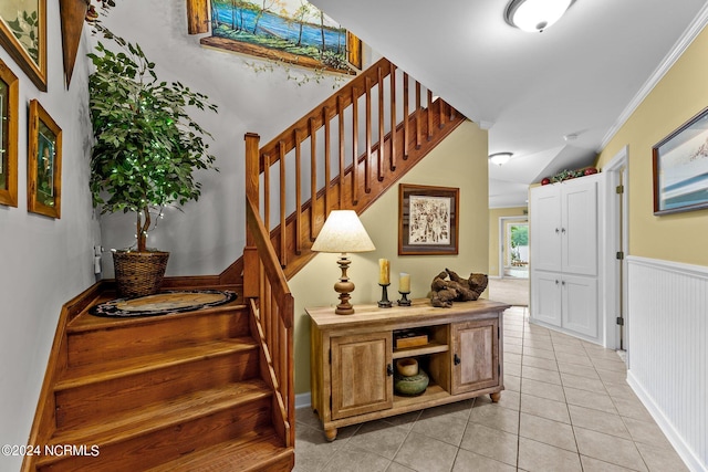 stairway with crown molding and light tile patterned floors