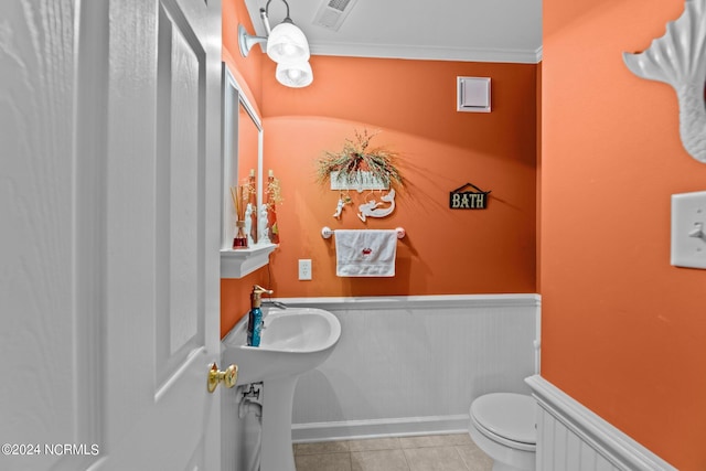 half bath featuring toilet, visible vents, wainscoting, tile patterned floors, and crown molding