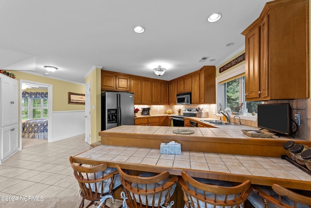 kitchen with light tile patterned floors, decorative backsplash, appliances with stainless steel finishes, tile counters, and sink