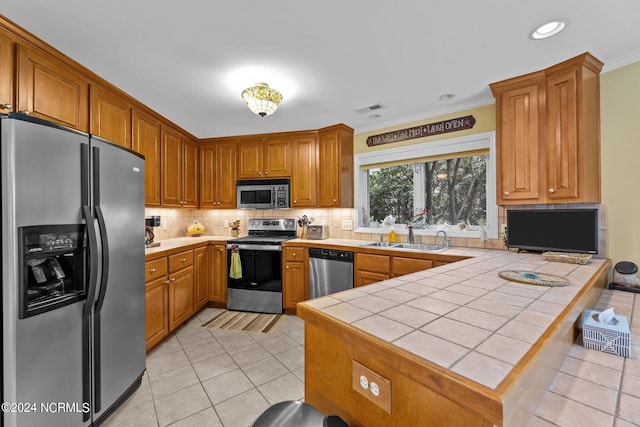 kitchen with stainless steel appliances, tile counters, sink, tasteful backsplash, and ornamental molding