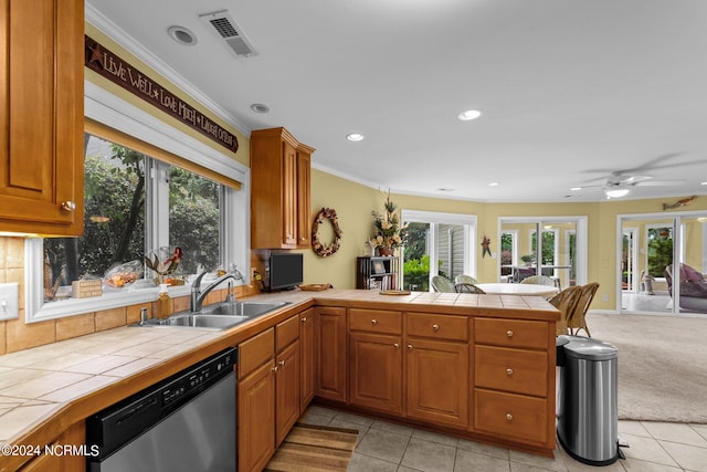 kitchen featuring light carpet, tile counters, stainless steel dishwasher, sink, and kitchen peninsula