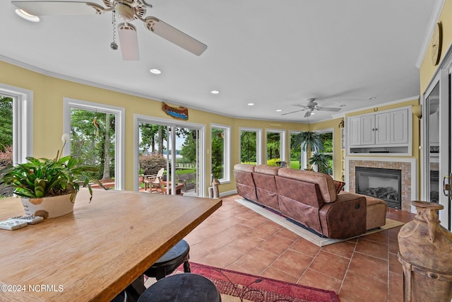 tiled living room featuring ceiling fan, crown molding, and a tile fireplace