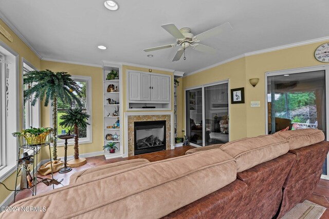 tiled living area featuring recessed lighting, a glass covered fireplace, a wealth of natural light, and crown molding