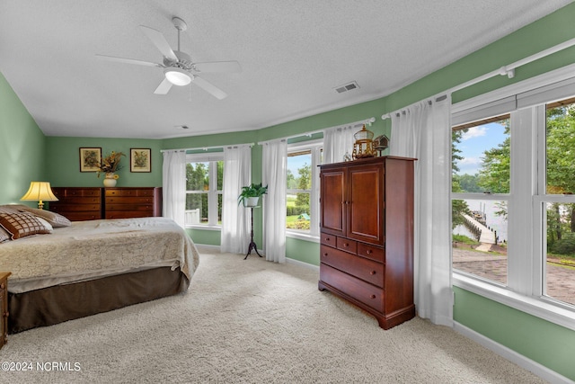 bedroom with visible vents, a ceiling fan, light carpet, a textured ceiling, and baseboards