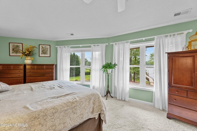 bedroom with ceiling fan, a textured ceiling, and light carpet