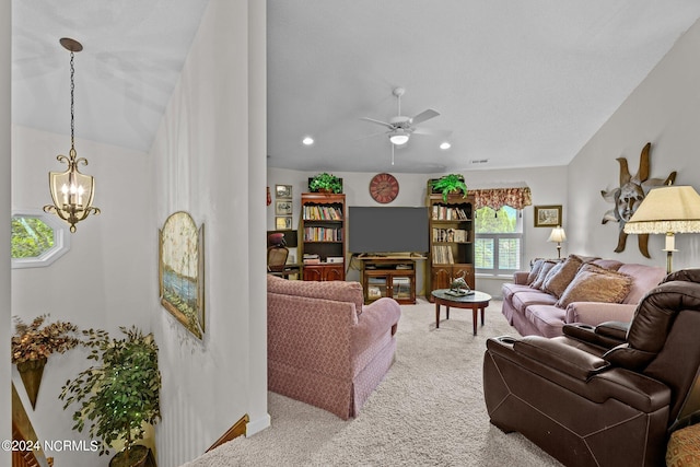 carpeted living room with ceiling fan with notable chandelier