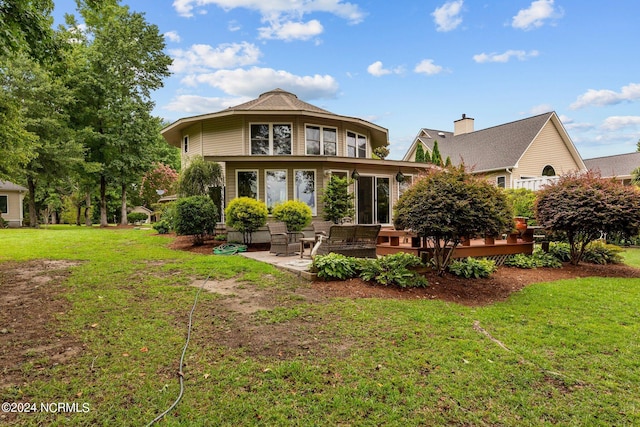 rear view of property featuring a patio area, a wooden deck, and a yard