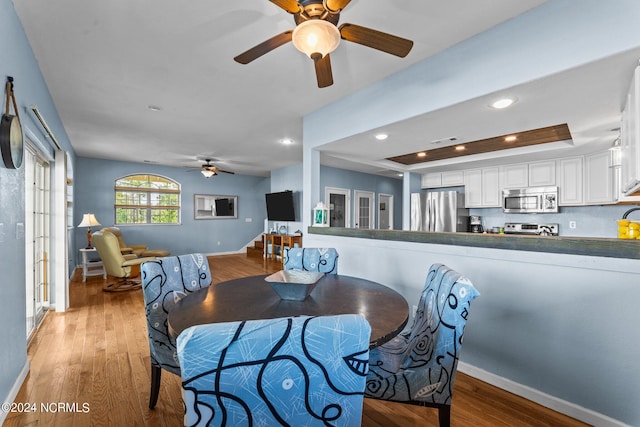 dining space with a tray ceiling, hardwood / wood-style floors, and ceiling fan