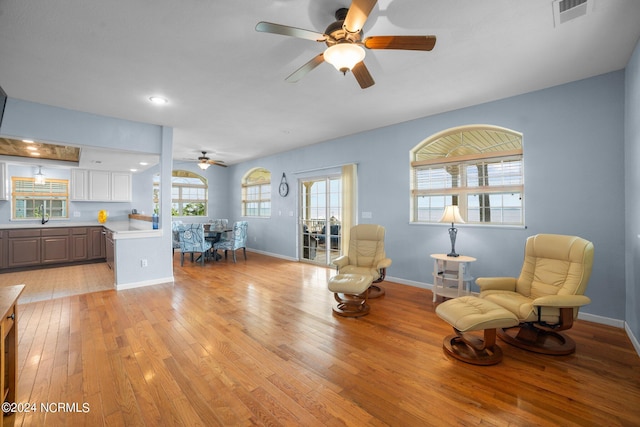 living area with a ceiling fan, light wood-type flooring, visible vents, and baseboards