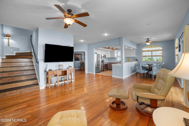 living room with ceiling fan and light hardwood / wood-style flooring